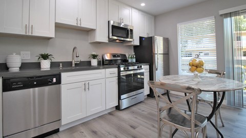 a kitchen with stainless steel appliances and a table with chairs